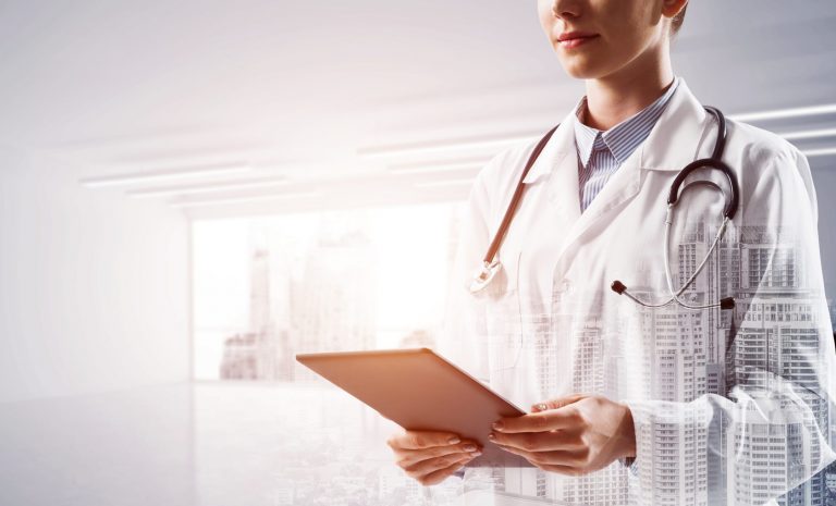 Double exposure of young female doctor holding tablet in hands while standing at white medical office and modern cityscape. Modern technologies for medical industry.